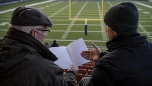 Supporters discussing a program above an American football field